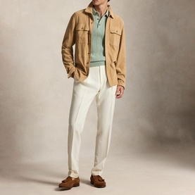 Model wearing a tan suede overshirt, styled with a mint green knit, white trousers and brown suede loafers