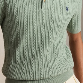 Model wearing Polo Ralph Lauren sage green cable-knit short-sleeve polo shirt, navy pony logo detail visible at chest