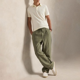 Model wearing Ralph Lauren pale cream polo shirt, styled with olive green linen trousers and white trainers
