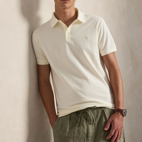 Model wearing Ralph Lauren pale cream polo shirt with embroidered pony logo, styled with khaki drawstring trousers and a watch.