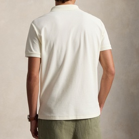 Model wearing Ralph Lauren pale cream polo shirt, back view, styled with olive green trousers.