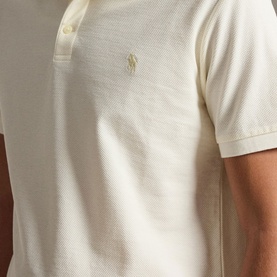 Model wearing Ralph Lauren pale cream pique polo shirt with tonal embroidered pony logo at chest, short sleeves visible