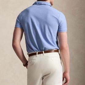 Model wearing light blue short-sleeve polo shirt, styled with cream trousers and brown leather belt, rear view