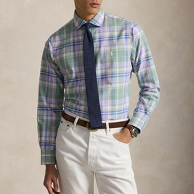 Model wearing Ralph Lauren Reg Shirt in faded mint lavender multi plaid, styled with navy tie, white trousers and brown belt
