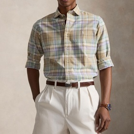 Model wearing Ralph Lauren Reg Shirt in khaki faded mint plaid, styled with white trousers and brown belt, sleeves rolled up.