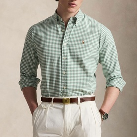 Model wearing green and white gingham check shirt with embroidered logo, styled with white trousers and brown belt