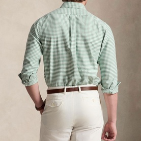 Model wearing a green and white gingham check shirt, sleeves rolled up, styled with a brown belt and cream chinos, rear view.
