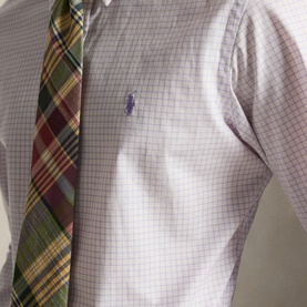 Model wearing Ralph Lauren Reg Shirt in powder purple white check, styled with a green and red plaid tie. Purple pony logo visible.