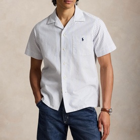 Model wearing Ralph Lauren white royal stripe short-sleeve camp collar shirt, styled with blue jeans and a watch.
