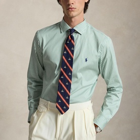 Model wearing Ralph Lauren Reg Shirt in faded mint and white stripe, styled with a navy striped tie and cream trousers