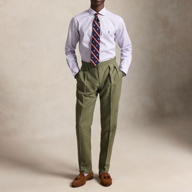 Model wearing Ralph Lauren Powder Purple White Reg Shirt with striped tie, olive pleated trousers and tan loafers.