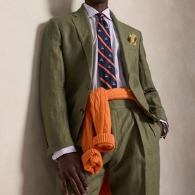 Model wearing Ralph Lauren Reg Shirt in powder purple white stripe, styled with olive green suit, navy tie, and orange knitwear
