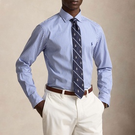 Model wearing Ralph Lauren blue stripe regular fit shirt with navy patterned tie, cream chinos and brown belt.