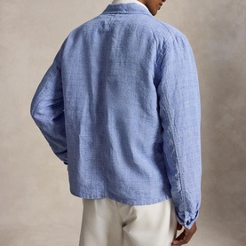 Model wearing a blue linen shirt, back view, styled with white trousers