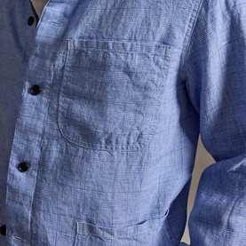 Close-up of blue chambray shirt showing chest patch pocket and dark button fastening detail