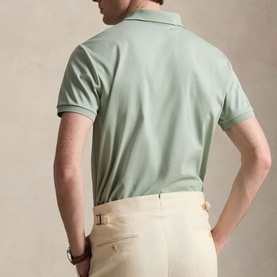 Model wearing Ralph Lauren light green regular polo shirt, rear view, styled with cream tailored trousers