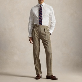 Model wearing Ralph Lauren white single cuff regular shirt with tie, styled with taupe pleated trousers and brown loafers