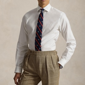 Model wearing Ralph Lauren white single cuff regular fit formal shirt, styled with a navy patterned tie and tan houndstooth trousers.