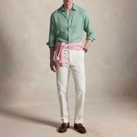 Model wearing Ralph Lauren Faded Mint slim shirt with pink knotted jumper, white tailored trousers and brown tassel loafers.