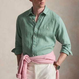 Model wearing Ralph Lauren Faded Mint slim linen shirt with sleeves rolled, styled with white trousers and pink knitwear tied at waist.