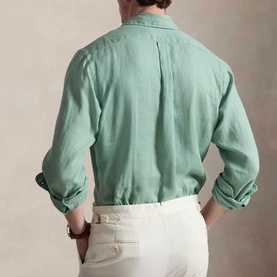 Model wearing Ralph Lauren Slim Shirt in faded mint linen, back view with box pleat, rolled cuffs, styled with cream trousers.