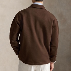Model wearing Ralph Lauren Nutmeg Brown sweatshirt, rear view, styled with white trousers and light blue shirt collar visible.