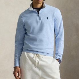 Model wearing Ralph Lauren Office Blue quarter-zip sweatshirt with embroidered pony logo, styled with a striped shirt and cream joggers.