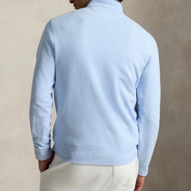 Model wearing Ralph Lauren office blue quarter-zip sweatshirt, back view, styled with white trousers