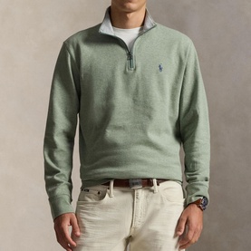 Model wearing Ralph Lauren green quarter-zip sweatshirt with embroidered pony logo, styled with checked shirt and cream chinos.