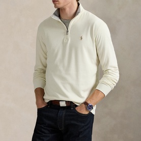 Model wearing Ralph Lauren cream quarter-zip sweatshirt with embroidered pony logo, styled with dark navy jeans and brown leather belt.