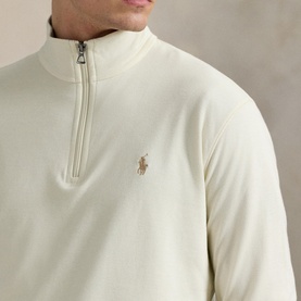 Model wearing Ralph Lauren cream quarter-zip sweatshirt with embroidered Polo Pony logo and silver zip detail.
