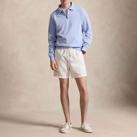 Model wearing Ralph Lauren Pebble Blue sweatshirt with open polo collar, styled with cream shorts and white trainers.