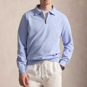 Model wearing Ralph Lauren pebble blue quarter-zip sweatshirt with polo collar, styled with cream drawstring trousers and a watch.