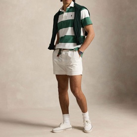 Model wearing Ralph Lauren green and white striped rugby shirt with white shorts and white high-top trainers, jacket draped over shoulders