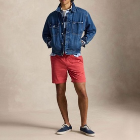 Model wearing Ralph Lauren sweatshirt in Light Navy/Eliteblue, styled with red shorts, denim jacket, and navy canvas shoes.