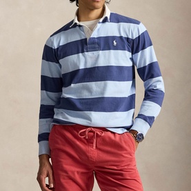 Model wearing Ralph Lauren light navy and elite blue wide stripe rugby sweatshirt, styled with red drawstring trousers