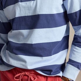 Model wearing Ralph Lauren light navy and elite blue wide-stripe sweatshirt, styled with red shorts, close-up mid-section view.