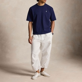 Model wearing Ralph Lauren Newport Navy T-shirt with white parachute trousers and white trainers