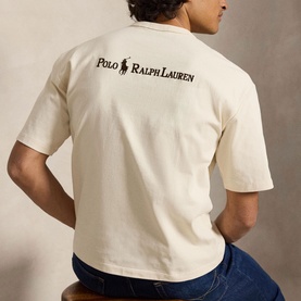 Model wearing Ralph Lauren T-shirt in Guided Cream, back view showing logo print, styled with blue jeans