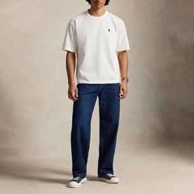 Model wearing Ralph Lauren white crew-neck T-shirt with embroidered pony logo, styled with dark blue jeans and navy trainers.