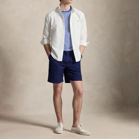 Model wearing Ralph Lauren New Iris Blue/White striped T-shirt, styled with white overshirt, navy shorts, and cream trainers.
