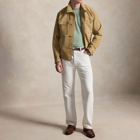 Model wearing tan overshirt jacket with chest pockets, styled with mint green tee, white trousers, and brown loafers