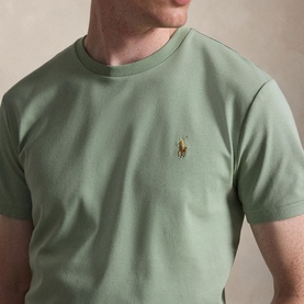 Model wearing sage green crew neck T-shirt with embroidered gold Polo Ralph Lauren pony logo at chest