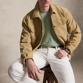 Model wearing tan zip-front overshirt jacket with chest pockets, styled with green crew-neck tee, white trousers and a watch
