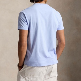 Model wearing Ralph Lauren pebble blue crew neck T-shirt, back view, styled with cream trousers.