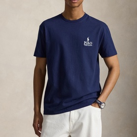 Model wearing Ralph Lauren Newport Navy T-shirt with small Polo logo on chest, styled with white trousers and a watch