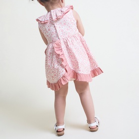 Model wearing Street Monkey Pink Print 2-piece baby set with floral ruffle dress and matching bloomers, rear view, styled with white sandals