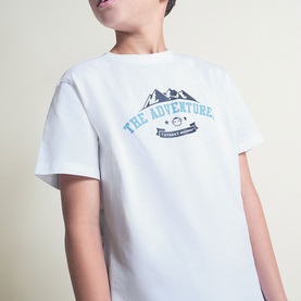 Model wearing Street Monkey white 2-piece set, featuring a white T-shirt with blue mountain "The Adventure" graphic print.