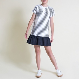 Model wearing Street Monkey white and navy stripe dress with ruffle hem skirt, styled with white trainers