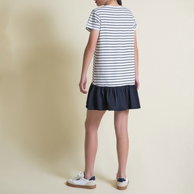 Model wearing Street Monkey White/Navy stripe dress with frill hem, styled with white trainers, rear view